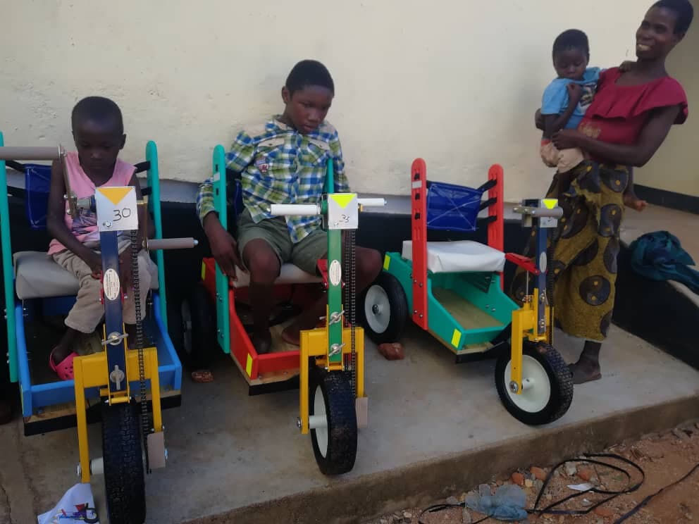 Children with their new adapted mobility tricycles, alongside a parent and infant