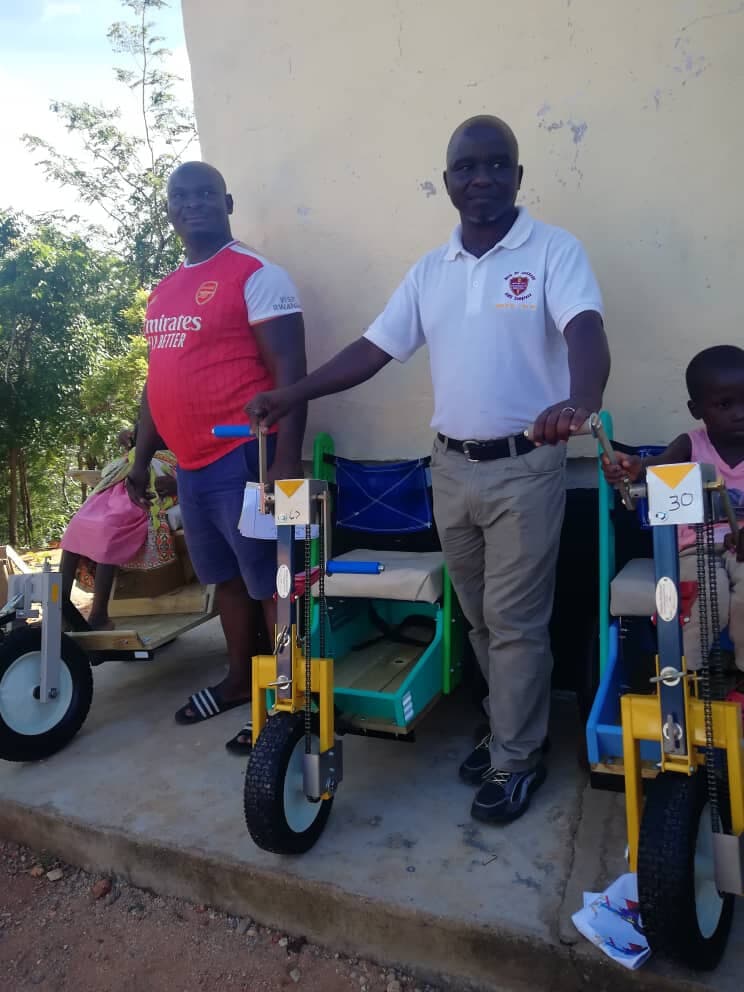 RECOAT staff handing over adapted mobility tricycles for children with disabilities